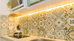 A kitchen with patterned tiles, a stainless steel sink, and a gas stove. - Cozy Stay Studio Apartment At B Residence Near Aeon Mall (Pagedangan)