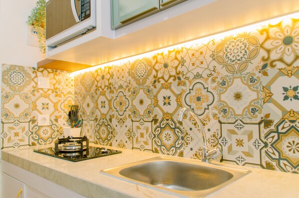 A kitchen with patterned tiles, a stainless steel sink, and a gas stove.