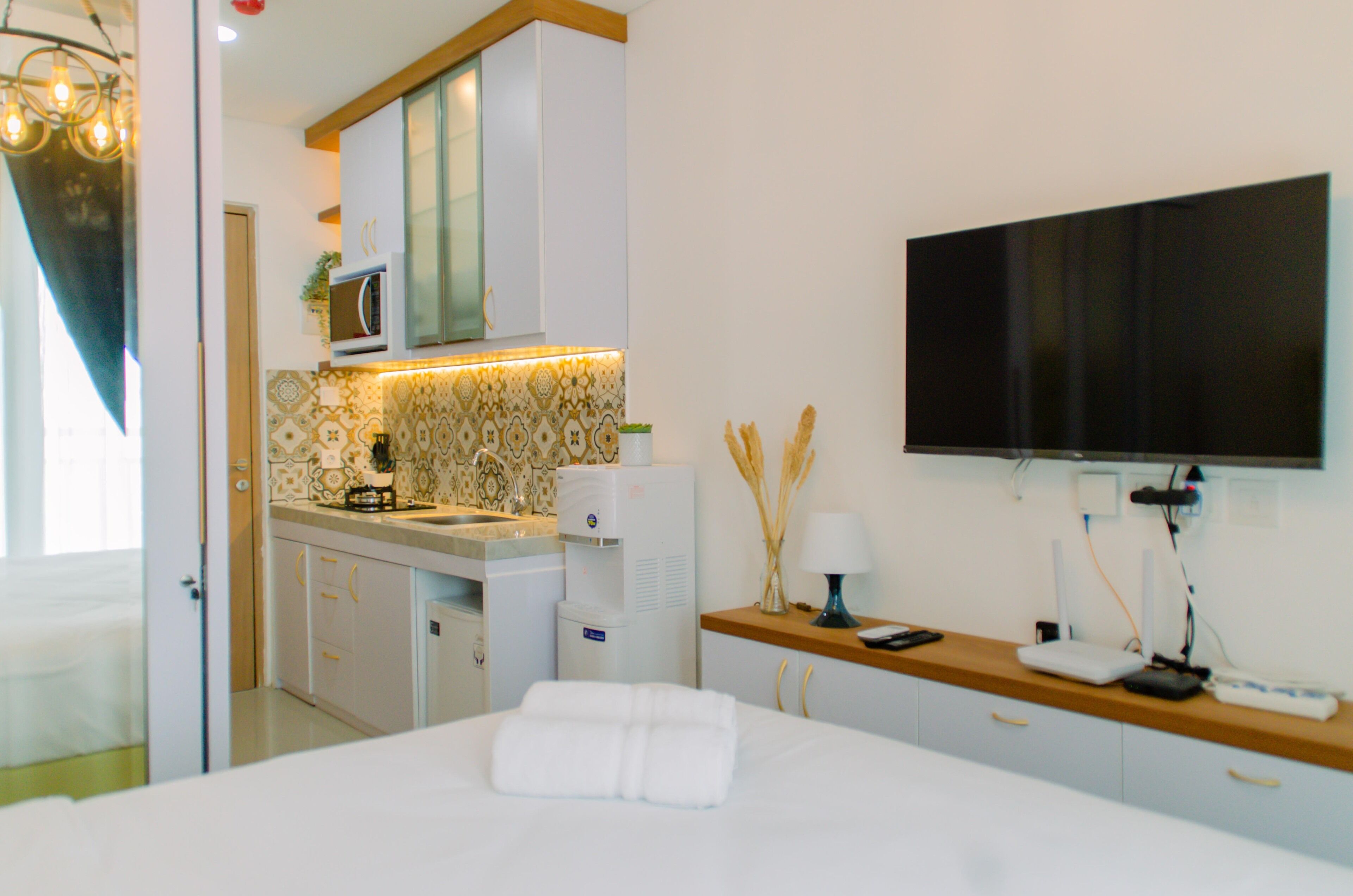 A hotel room with a bed, a TV, a microwave, a coffee machine, and a small kitchenette.