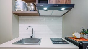 A kitchen with a stainless steel sink, a Rinnai range hood, and a digital scale on the countertop. - Comfortable Pool View Studio Room at LRT City Jatibening Apartment (Bekasi)