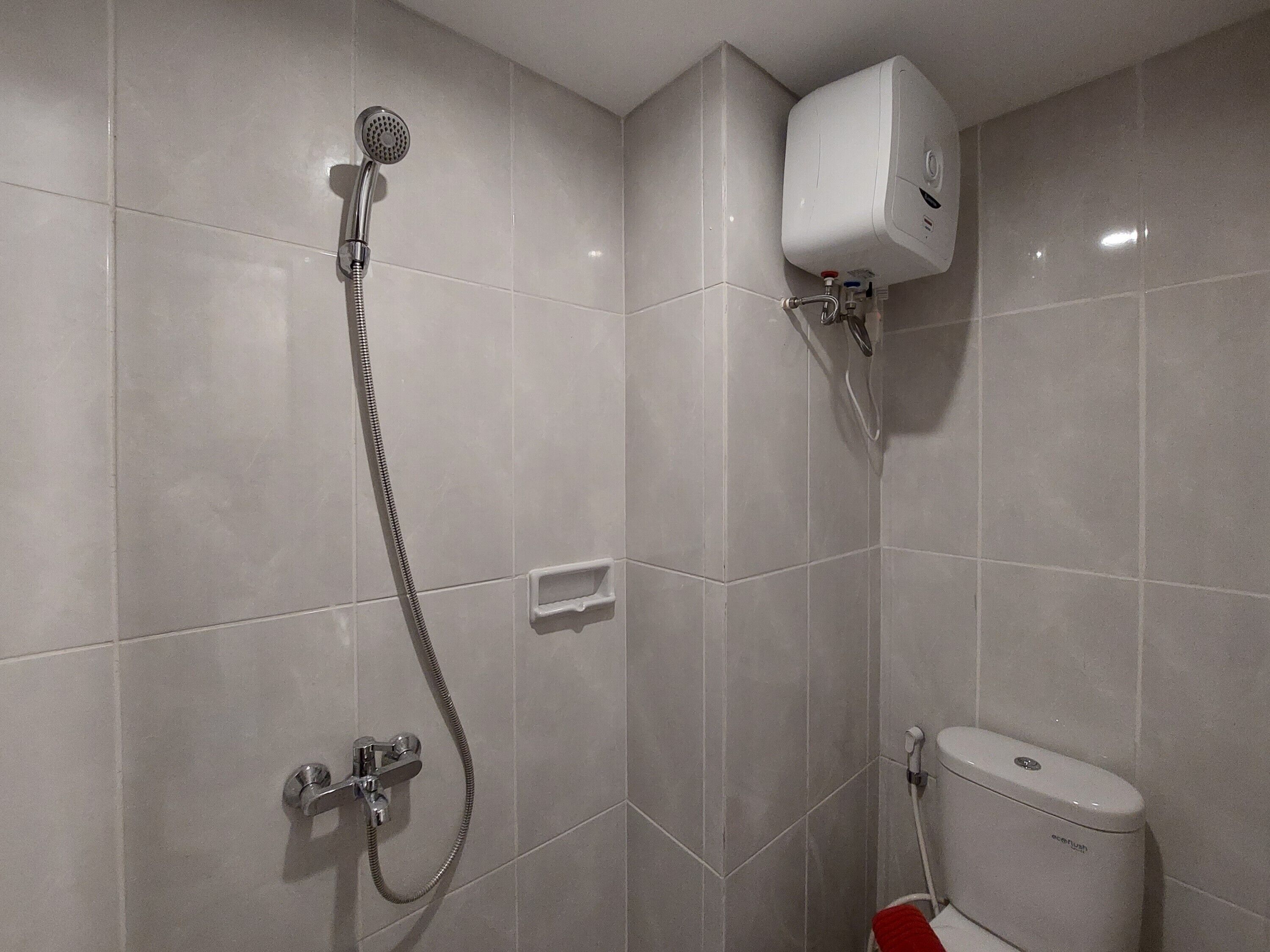 A bathroom with a shower, toilet, and a water heater.