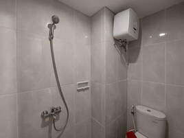 Un baño con ducha, inodoro y calentador de agua.