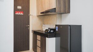 Una cocina compacta con un refrigerador, un microondas y una cafetera sobre la encimera.