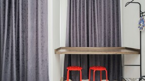 Una habitación con un estante de madera, dos taburetes rojos y una cortina.