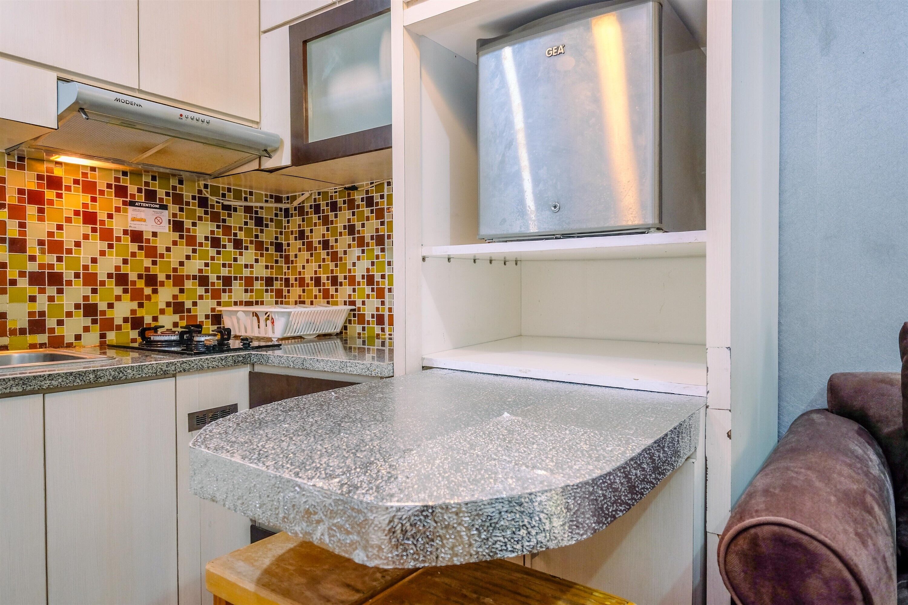 A compact kitchen with a tiled backsplash, a stainless steel range hood, and a countertop.