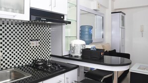 Una cucina compatta con zanzariera a quadri bianchi e neri, un fornello a gas, una macchina da caffè e un erogatore d'acqua.
