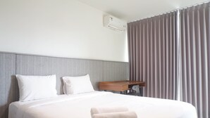 A hotel room with a neatly made bed, a bedside table, and a large window with curtains.