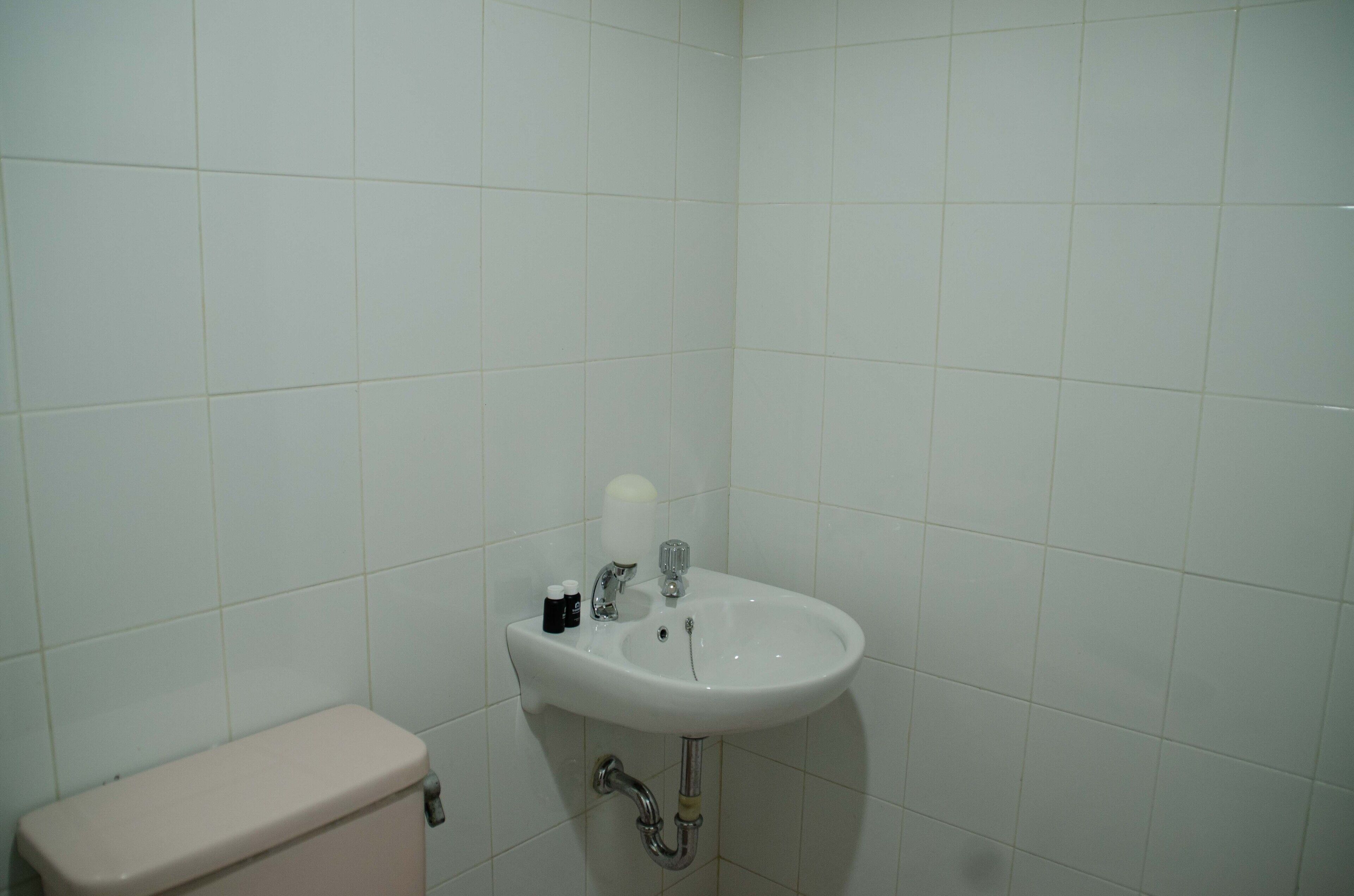 Une salle de bain avec un lavabo blanc, des toilettes et des murs carrelés.