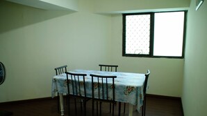 Un coin repas avec une table et des chaises, une fenêtre avec des stores et un ventilateur fixé au mur.