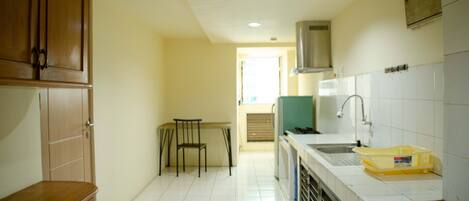 A kitchen with white tiled floors, wooden cabinets, a sink, and a chair.