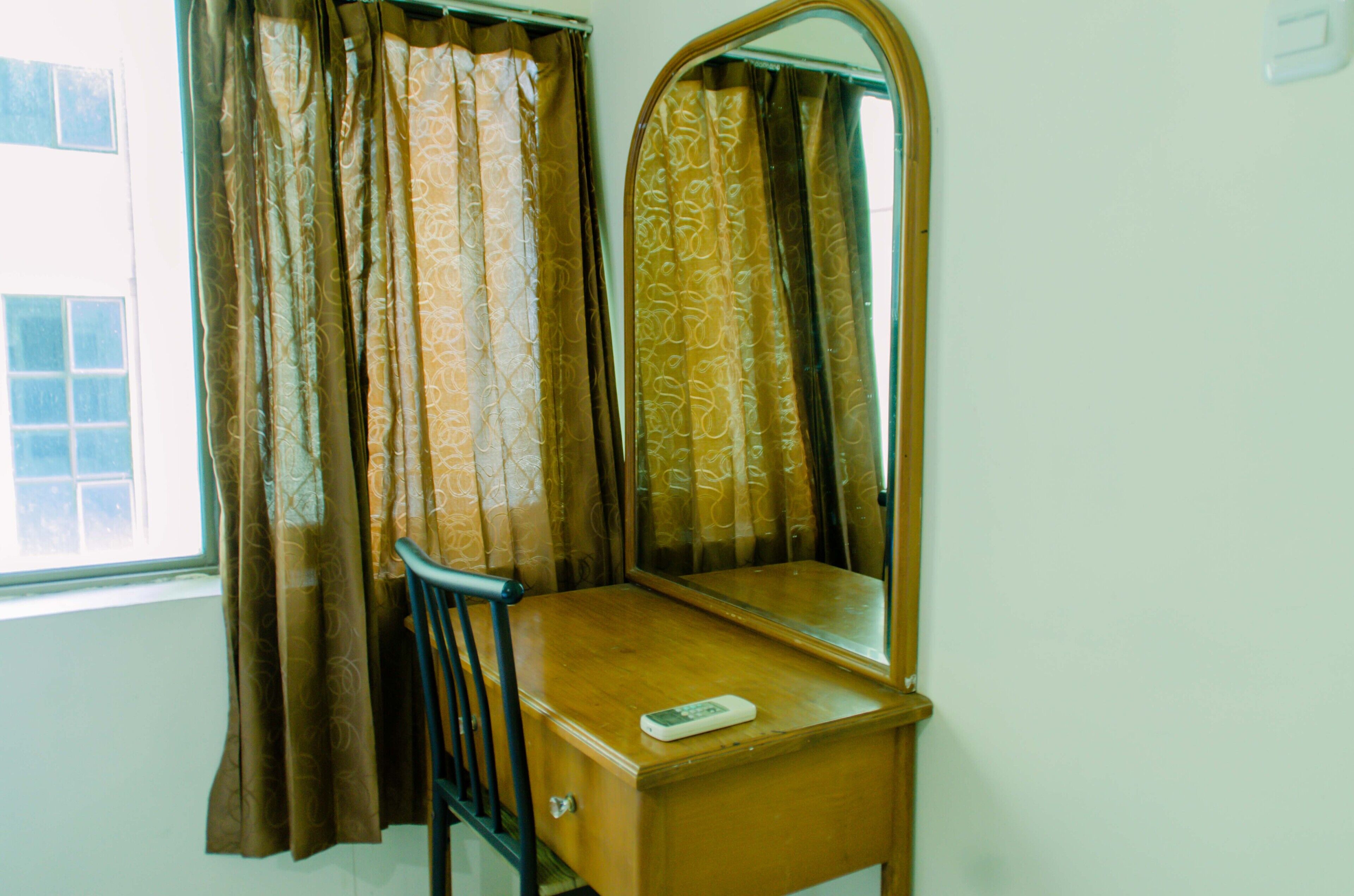 A wooden vanity with a mirror and a remote control on it.