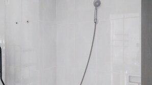 A shower with a handheld showerhead and a wall-mounted faucet. - Comfy And Minimalist Studio Room At Serpong Garden Apartment (Cisauk)