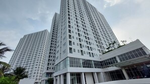 A modern high-rise building with a glass facade and multiple balconies. - Comfy And Minimalist Studio Room At Serpong Garden Apartment (Cisauk)