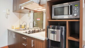 A kitchen with a stainless steel microwave, a built-in oven, and a refrigerator. - Minimalist And Comfort Studio At Tamansari The Hive Apartment (Jakarta)