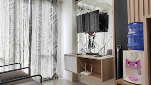 Ein Hotelzimmer mit Schreibtisch, großem Spiegel, Wasserspender und Vorhang mit Blättermotiv.