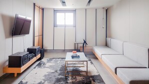 A modern living room with a flat-screen TV, a sofa, a coffee table, and a sound system.