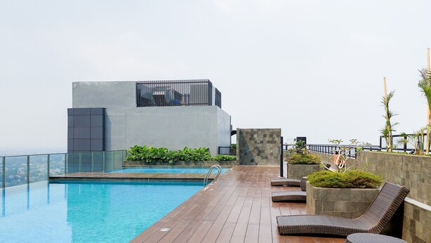 Ein Poolbereich auf dem Dach mit einem modernen Pool, Liegestühlen und Blick auf die Stadt.