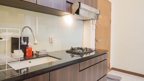 A modern kitchen with a black countertop, stainless steel faucet, and a gas stove. - Cozy Stay 1Br At Maple Park Apartment Near Sunter (Jakarta)