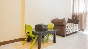 A small room with a sofa, two chairs, a table, and a travel bag. - Cozy Stay 1Br At Maple Park Apartment Near Sunter (Jakarta)