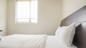 A neatly made bed with white linens in a room with a window and a dark headboard. - Cozy Stay 1Br At Maple Park Apartment Near Sunter (Jakarta)