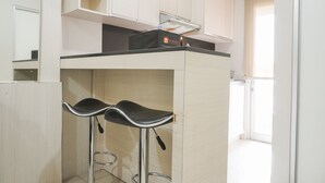 A compact kitchen with a countertop and two bar stools. - Comfort And Simply 2Br At Green Bay Pluit Apartment (Jakarta)