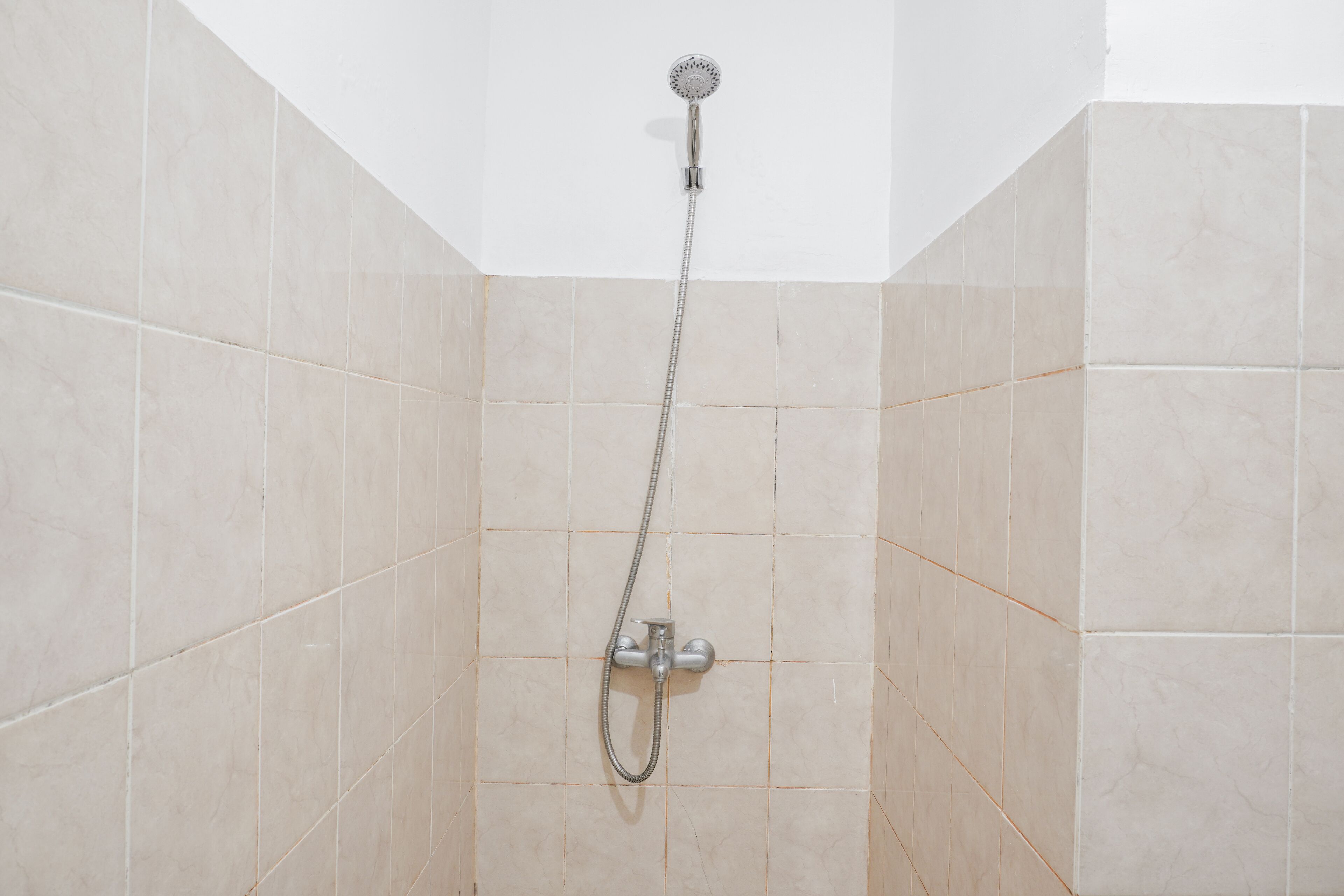 A shower with a handheld showerhead and a wall-mounted faucet.