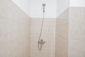 Eine Dusche mit Handbrause und Armaturen an der Wand.