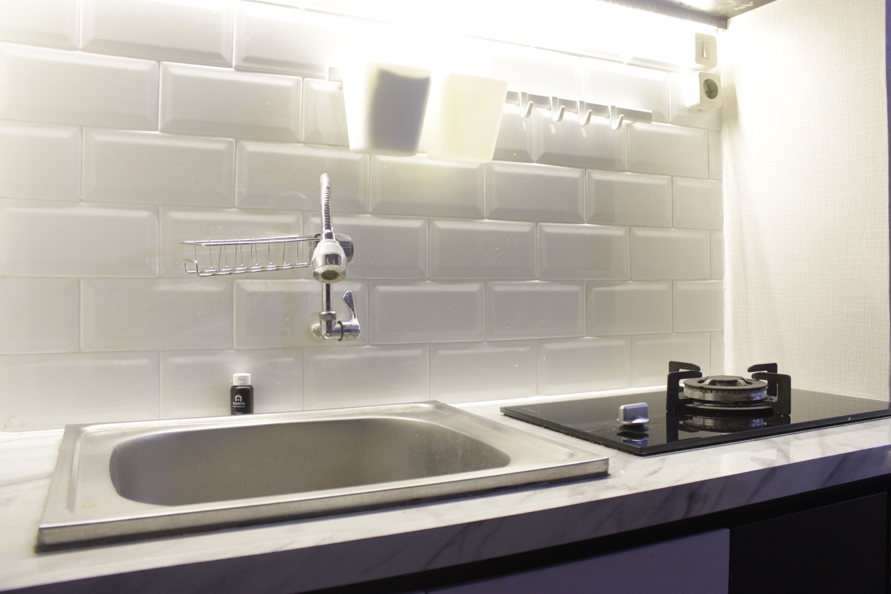 A kitchen with a stainless steel sink, a gas stove, and white subway tiles on the backsplash.
