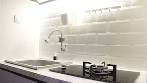 Uma cozinha moderna com pia dupla, fogão a gás e painel de azulejos branco.