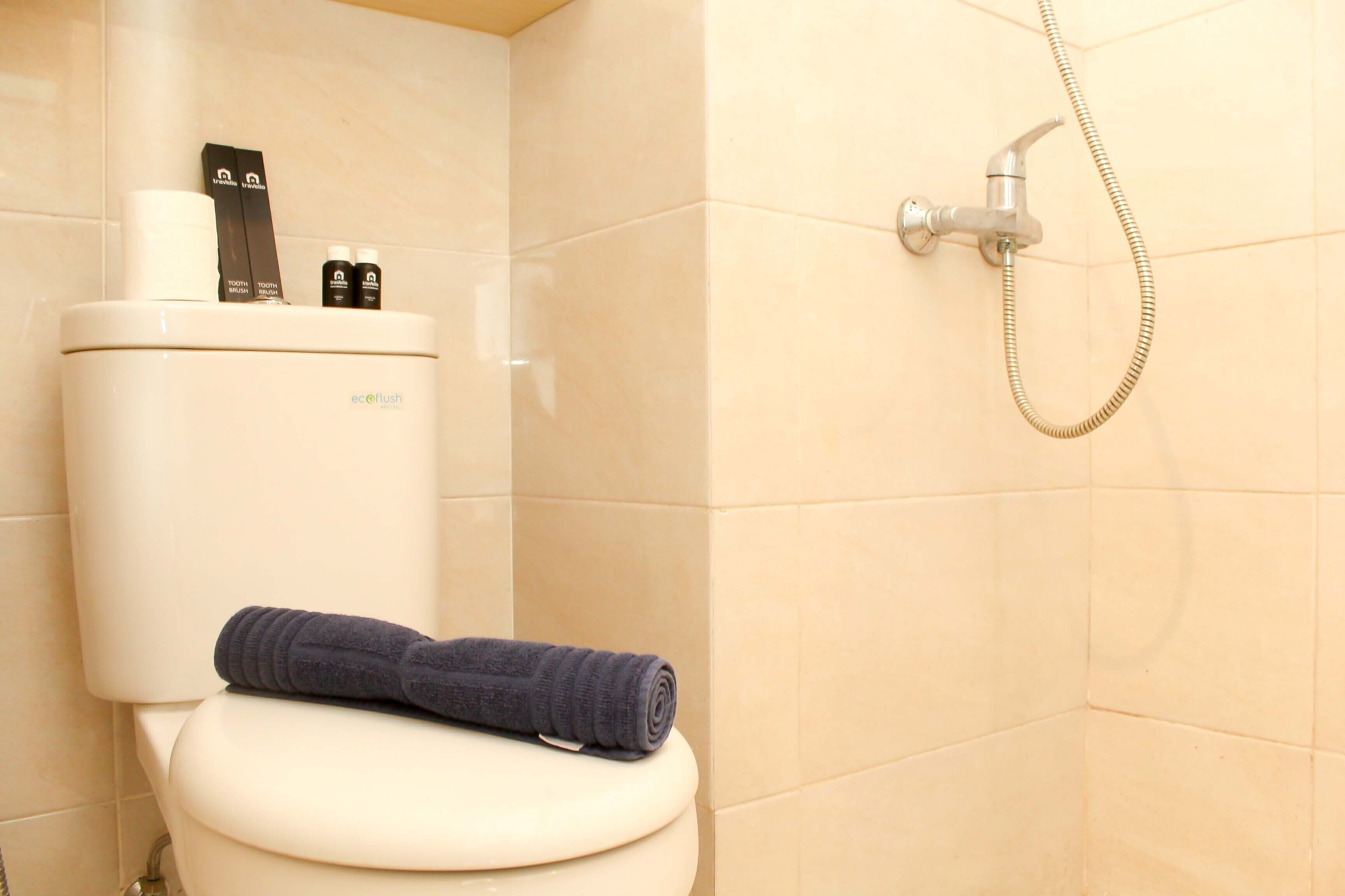 Een badkamer met een toilet, een douche en een handdoek op de toiletbril.