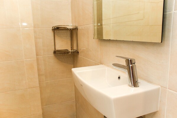Un baño con un lavamanos blanco, grifo cromado y un espejo encima.