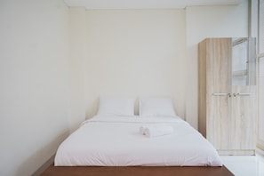 A minimalist bedroom with a wooden bed frame, white bedding, and a wooden wardrobe.