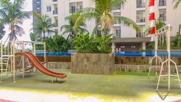 A playground with a slide, swings, and a pool area.