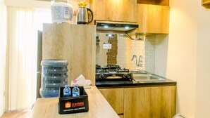 A compact kitchen with wooden cabinets, a gas stove, a sink, and a water dispenser.