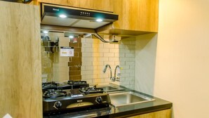 A kitchen with a gas stove, stainless steel sink, and wooden cabinets.
