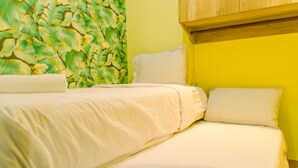 A bed with white bedding and a green leafy wall behind it.