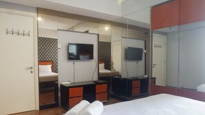 A hotel room with a bed, a TV, a dresser, and a mirror.