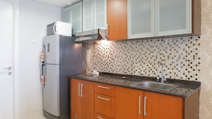 A kitchen with a refrigerator, microwave, sink, and wooden cabinets.