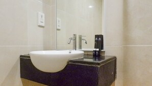A modern bathroom with a white sink, black countertop, and a mirror above the sink.