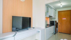 Una cucina moderna con TV integrata, mobili bianchi e una porta in legno.