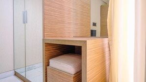 A modern bathroom with a wooden vanity, a mirror, and a built-in bench.
