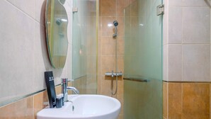 A bathroom with a white sink, a glass shower enclosure, and a mirror.