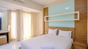 A hotel room with a large bed, a wooden headboard, a bedside table, a mirror, and a window with curtains.