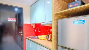 A compact kitchen with a black door, a red backsplash, and a stainless steel refrigerator.