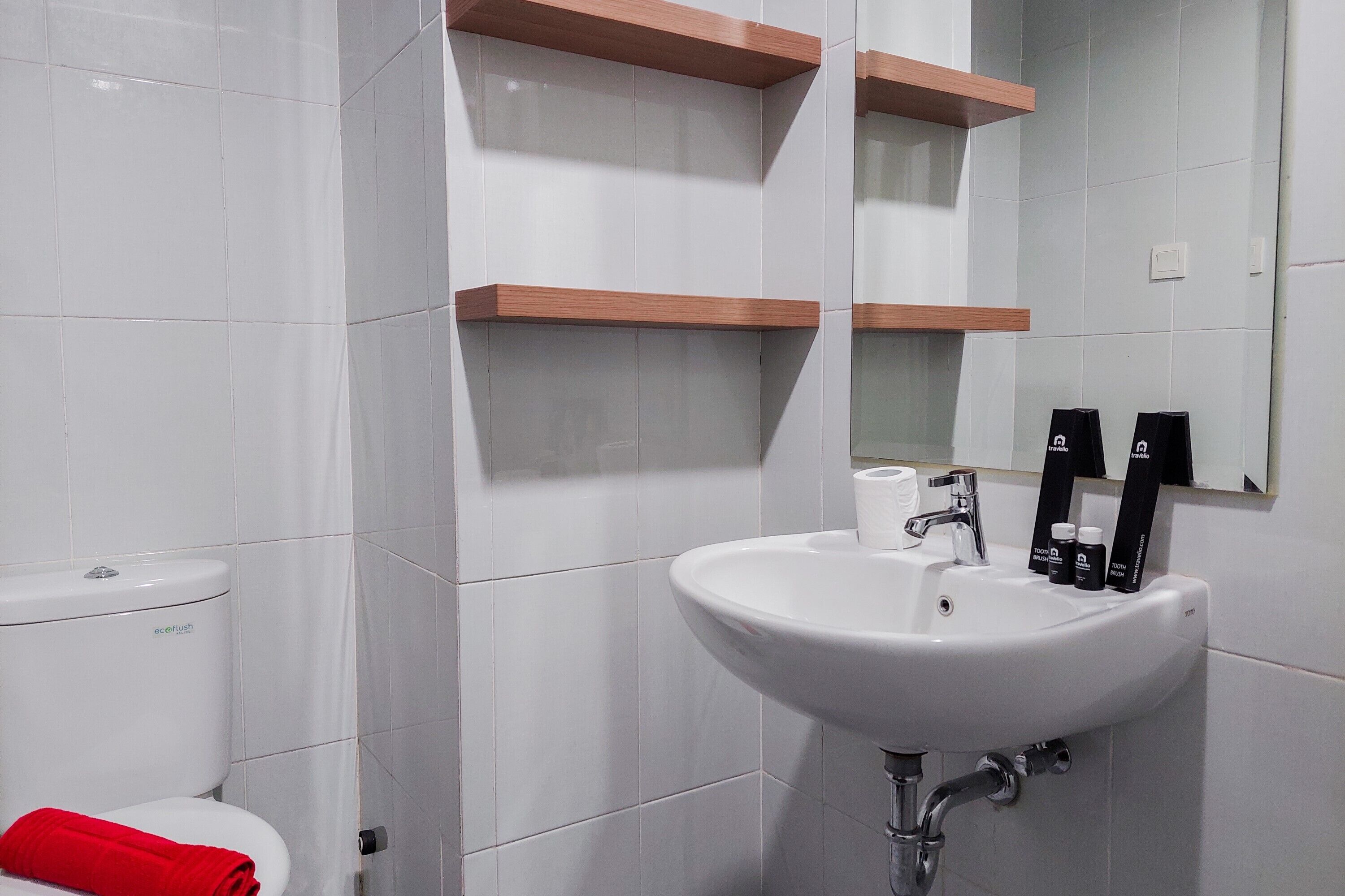 A modern bathroom with white tiles, a white sink, and two wooden shelves above it.