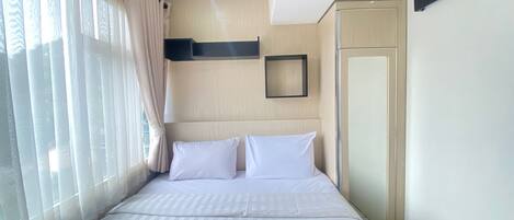 A hotel room with a bed, curtains, a television, and a door.