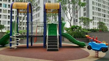 A playground with a slide, climbing structures, and a swing set.