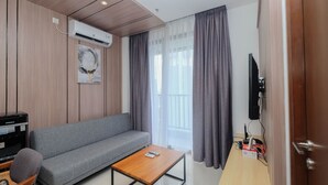 A modern living room with a grey sofa, a wooden coffee table, and a TV on a wooden stand.
