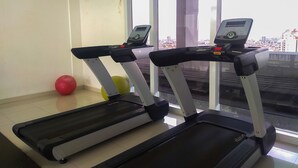 Two treadmills with digital displays, a red exercise ball, and a window with a city view. - Minimalist And Comfort Studio Apartment At Springhill Terrace Residence (Jakarta)
