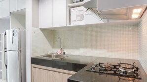 A modern kitchen with a stainless steel refrigerator, a sink, and a gas stove. - Minimalist And Comfort Studio Apartment At Springhill Terrace Residence (Jakarta)